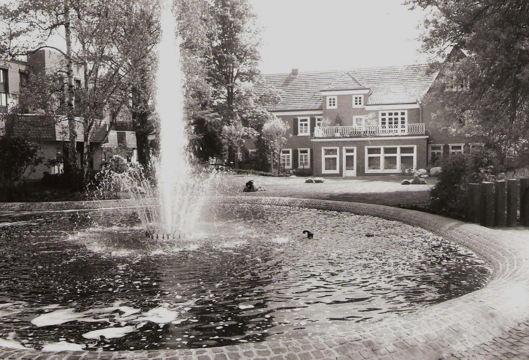 Eine schwarz-weiß Fotografie des Gebäudes in der Kirchstraße 21. Das Foto wurde aus Dem Garten des Hauses aufgenommen, im Vordergrund ist ein Springbrunnen zu sehen. 