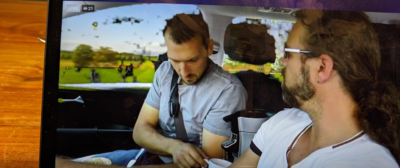 Auf einem Tablet-Bildschirm wird ein Bild von zwei Männern in einem Auto gezeigt.