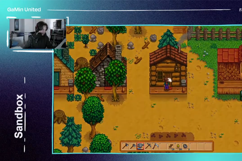 Ein Bildschirm mit einer Szene aus einem Computerspiel mit altmodischer Grafik. Eine Figur steht darin vor einem der vielen einfachen Holz- und Steinhäuser. Links oben auf dem Bildschirm ist eine Person, vermutlich der Spieler, mit Headset zu sehen. 