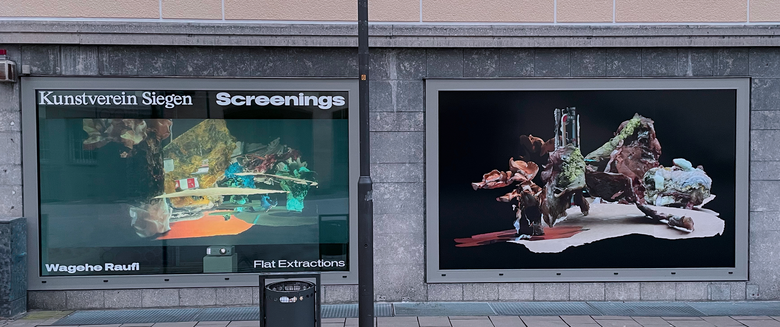 Zwei große Bildschirm an einer Hauswand, auf denen abstrakte Skulpturen zu sehen sind. Auf dem linken Bildschirm steht oben "Kunstverein Siegen - Screenings" und unten "Wagehe Raufi - Flat Extractions".