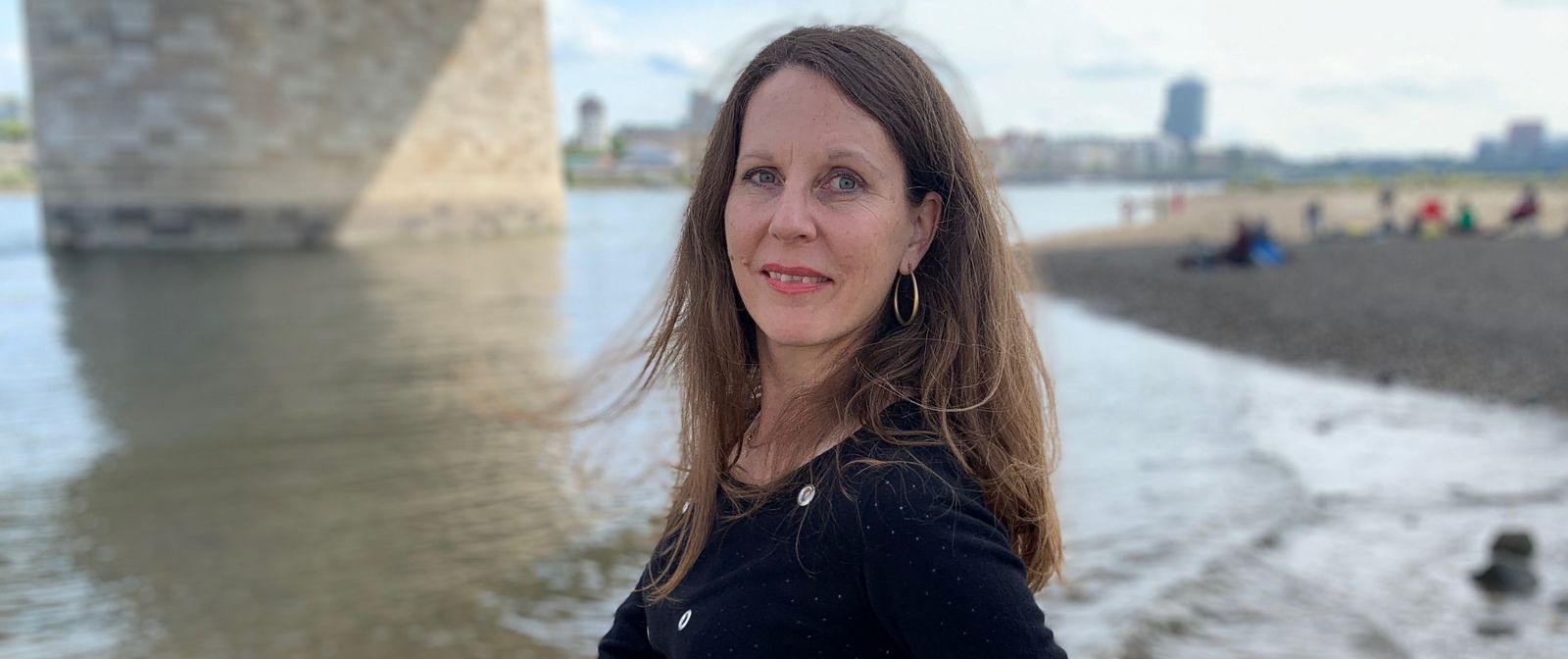 Autorin Petra Postert am Fluss unter einer Brücke.