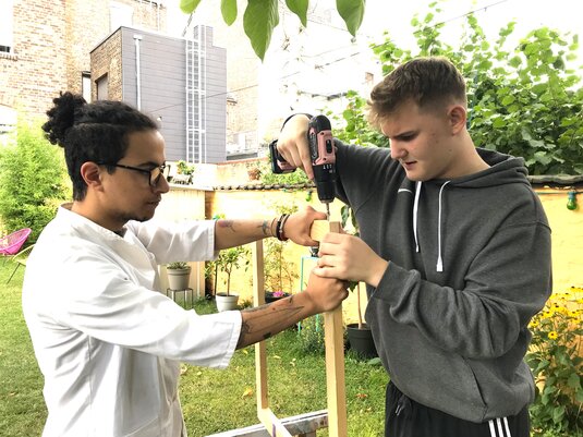 Zwei Jugendliche bauen einen Holzrahmen.